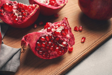 Wooden board with ripe pomegranates on table