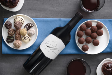 Delicious chocolate sweets and red wine on grey background