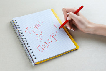 Female hand writing phrase TIME FOR CHANGE in notebook