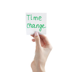 Female hand holding note with phrase TIME CHANGE on white background