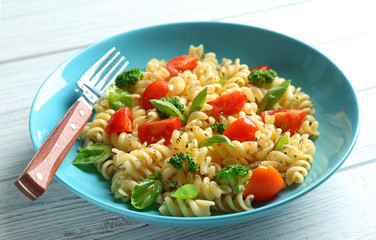 Pasta salad with tomatoes and broccoli on wooden table