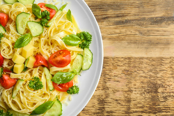 Pasta salad with tomatoes and cucumber on wooden background