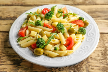 Pasta salad with tomatoes and olive on wooden background