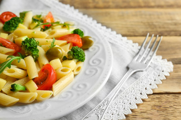 Pasta salad with tomatoes and olive on wooden table