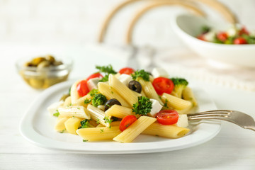 Pasta salad with tomatoes and olive on wooden table