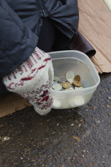 Coins of street beggar - hand in mitten holds conteiner with russian rubles, winter cold russia