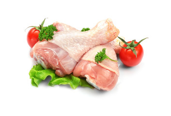 Raw chicken legs with lettuce and tomatoes on white background