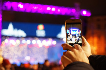 Fototapeta na wymiar Woman taking photo on smartphone at open air concert