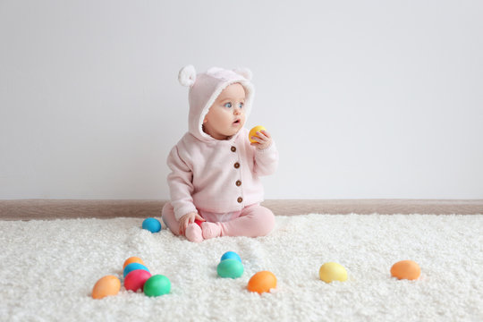 Cute funny baby with colorful Easter eggs at home
