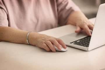 Fototapeta na wymiar Hands of elderly woman working on laptop
