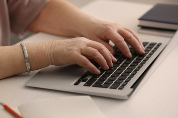 Fototapeta na wymiar Hands of elderly woman working on laptop