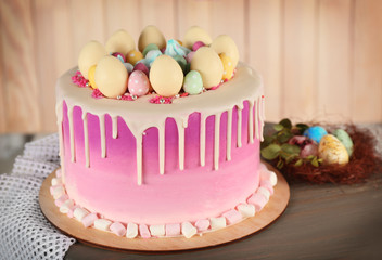 Delicious Easter cake decorated with colorful sweet eggs on wooden table