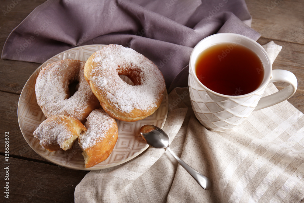 Wall mural Delicious homemade doughnuts and cup of tea on table