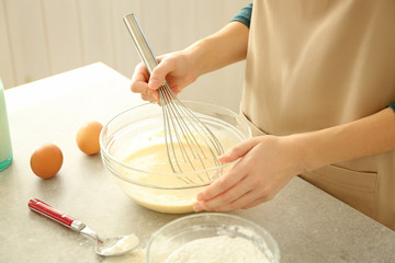 Woman making dough in glass bowl on table in kitchen