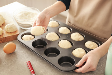 Obraz na płótnie Canvas Woman putting small balls of dough into baking shape at kitchen