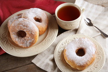 Delicious homemade doughnuts and cup of tea on table