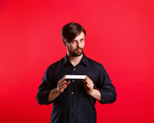 Man holding an empty copyspace. Advertising Space. Invitingly attractive man looking at the camera and holding a sign with both hands.