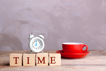 Cubes with alarm clock and cup on wooden table. Time concept