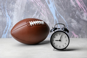 Alarm clock and football ball on color background
