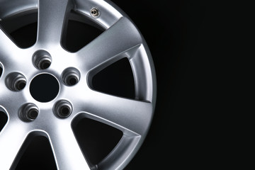 Obraz premium Silver alloy car wheel rim with five spokes and tire valve on black background, automotive industry and vehicle maintenance