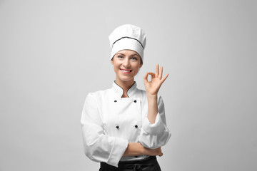 Portrait of female chef on light grey background