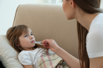 Mother giving her daughter medicines at home