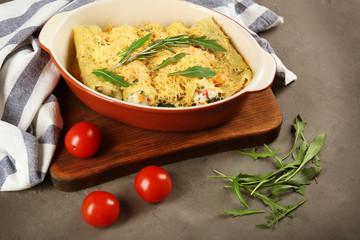 Delicious stuffed cannelloni in baking dish on table
