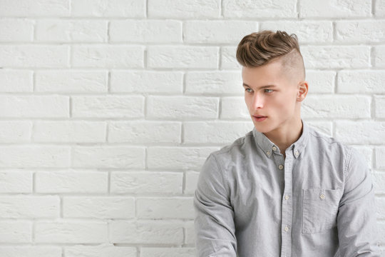 Handsome young man posing on white brick wall background