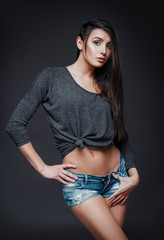 Studio fashion shot: portrait of pretty young girl in denim shorts and jersey