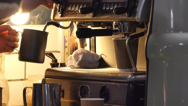 Close up of hands of two young men preparing aromatic brew on old style professional coffee machine in the kitchen of cafeteria 