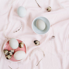 Obraz na płótnie Canvas White Easter eggs, quail eggs and feathers on pink textile background. Flat lay, top view. Traditional spring concept. Easter concept.