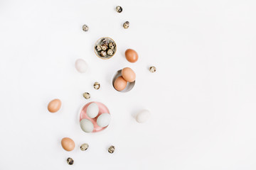 White and brown Easter eggs and quail eggs on white background. Flat lay, top view. Traditional spring concept.