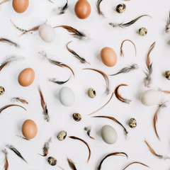 White and brown Easter eggs, quail eggs and feathers on white background. Flat lay, top view. Traditional spring concept.