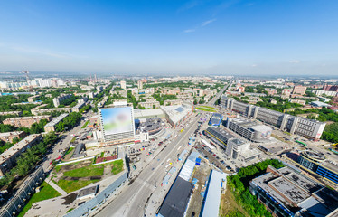 Aerial city view with crossroads and roads, houses, buildings, parks and parking lots, bridges. Copter shot. Panoramic image.