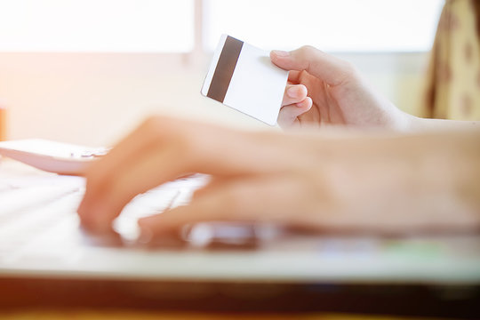 Woman's hands holding a credit card and using smart phone for online shopping.vintage tone