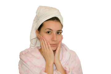 Young beautiful girl with towel on head and pink robe after bath rests on a white background 