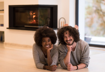 multiethnic couple lying on the floor  in front of fireplace