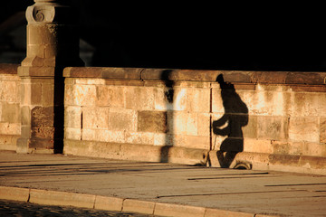 Shadows of cyclist on an old bridge in the morning
