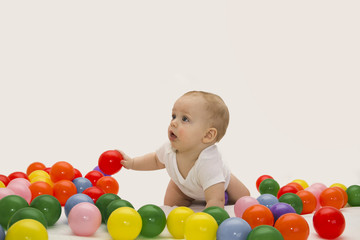 Fototapeta na wymiar 8 month baby boy playing with color balls. White background