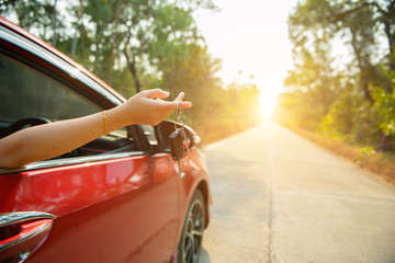 Happy woman hand out window car red and car key with sunlight