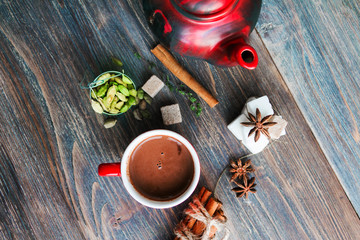Sooty teapot, sugar cubes and spices - anise, cinnamon, cardamom - on slate - ingredients for hot aromatic drinks