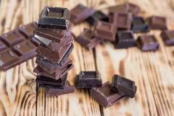 A tower made of milk and black chocolate pieces on a wooden background.