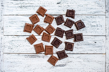 A heart shape made of chocolate pieces on a white wooden background