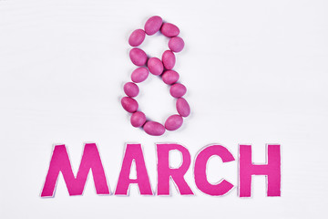 Dragee on white surface. Laconic congratulation for women.