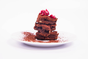 Heart shaped slices of a brownie decorated with pomegranate on white background