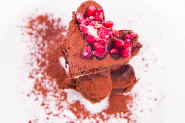 Heart shaped slices of a brownie decorated with pomegranate on white background