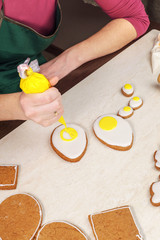 Drawing yolk on gingerbread shaped as an egg and coated with white glaze