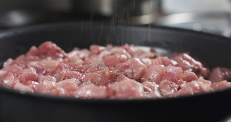 grinding pepper on pork meat frying on pan cooking pilaf, 4k photo