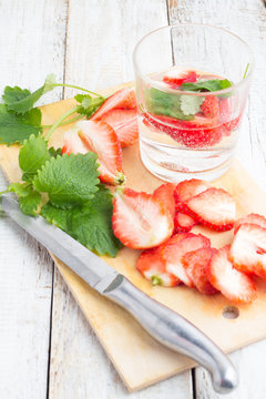glass of drink with strawberries and mint on a white wooden background