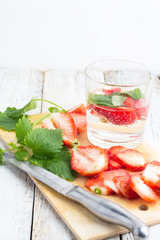 glass of drink with strawberries and mint on a white table
